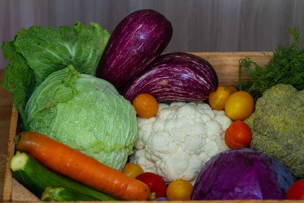 Fresh vegetables - cabbage, carrots, zucchini, eggplant and tomatoes in a wooden box in the store.