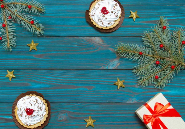 New Year\'s composition. Cakes and gift box with a red bow on a blue wooden background. Christmas, winter, new 2020 year concept. Flat lay. Top view and copy space.