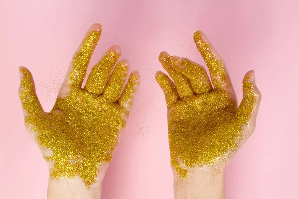 Female hands in gold sparkles. Sparkling hands on a light background.