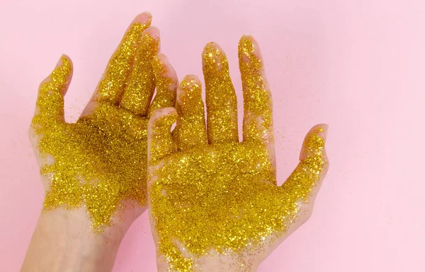 Female hands in gold sparkles. Sparkling hands on a light background.