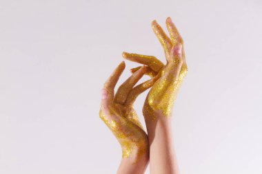 Female hands in gold sparkles. Sparkling hands on a light background. clipart