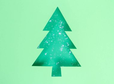 Geometrik düzlük. Noel ağacı şeklinde üçgen kağıt bir delikte suni kar. Güzel neo nane arkaplanı
