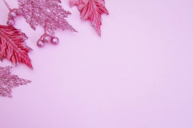 Açık renkli bir kağıt üzerinde parlak, pembe Noel yaprakları. Yeni yıl ve Noel konsepti. Mesaj için yer. Boş boşluk.