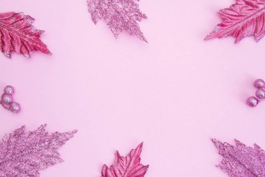 Açık renkli bir kağıt üzerinde parlak, pembe Noel yaprakları. Yeni yıl ve Noel konsepti. Mesaj için yer. Boş boşluk.