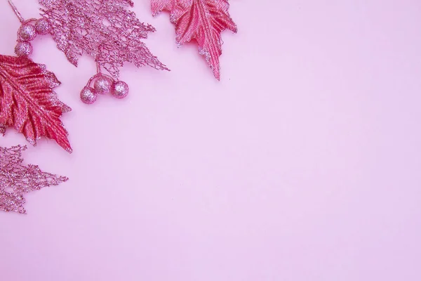 Açık renkli bir kağıt üzerinde parlak, pembe Noel yaprakları. Yeni yıl ve Noel konsepti. Mesaj için yer. Boş boşluk.
