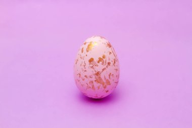 Paskalya yumurtası altın sarısı ve parlak pembe bir arka plan..