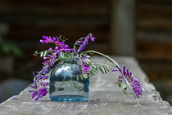 Красивые Фиолетовые Цветы Голубой Декоративной Бутылке Деревянном Столе Деревне — стоковое фото