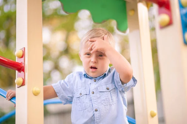 障害のある子供の日常生活 遊び場ではダウン症候群の少年が遊んでいます 赤ちゃんの染色体と遺伝性障害 — ストック写真