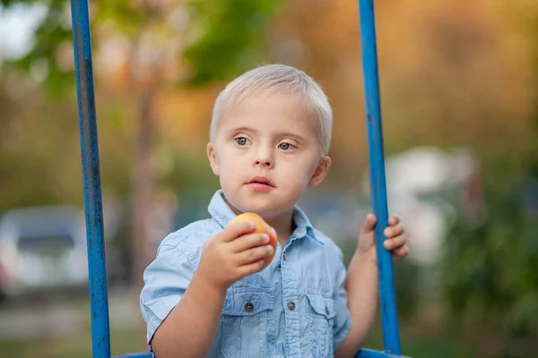 The daily life of a child with disabilities. A boy with Down Syndrome is playing in the playground. Chromosomal and genetic disorder in the baby.