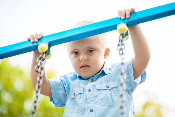 The daily life of a child with disabilities. A boy with Down Syndrome is playing in the playground. Chromosomal and genetic disorder in the baby.