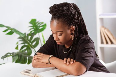 Masadaki ofiste oturan Afrikalı Amerikalı kız. İşyerindeki iş kadını.