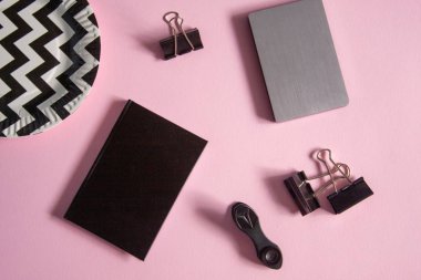 Pembe arka planda güzel, yumuşak bir daire. Not defteri, mandallar ve tabaklar masaya..