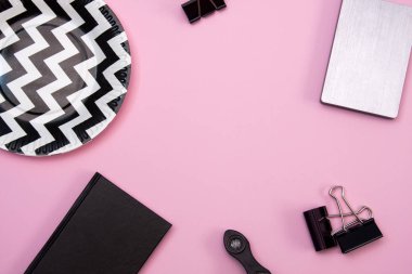 Pembe arka planda güzel, yumuşak bir daire. Not defteri, mandallar ve tabaklar masaya..