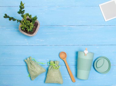  Masanın üzerinde yeşil bir bardak bambu ve iki yeşil torba var. Sıfır atık.