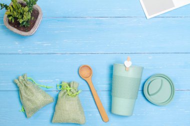  Masanın üzerinde yeşil bir bardak bambu ve iki yeşil torba var. Sıfır atık.