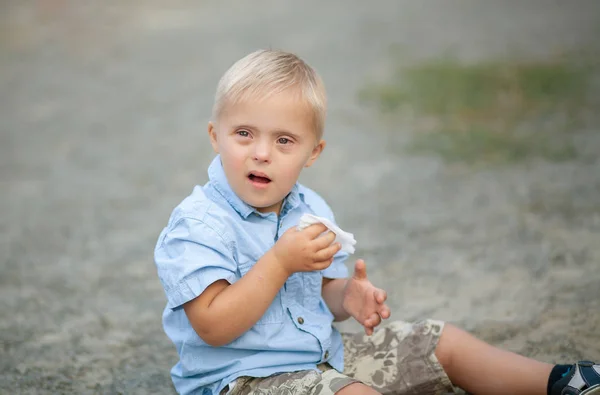 The daily life of a child with disabilities. A boy with Down Syndrome is playing in the playground. Chromosomal and genetic disorder in the baby.