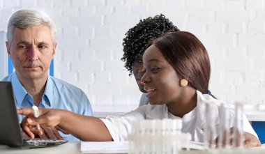 Kafkasyalı kıdemli takım lideri ve test laboratuarında çalışan iki Afrikalı kadın sıhhiyeci Corona virüsü için hasta örneklerini tartışıyorlar. Enerjik ekipte laboratuvar çalışması