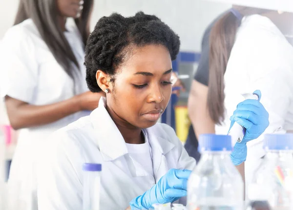 Female African medical students, young graduates in research laboratory or medical test lab performing various testing on samples.Female researcher does pcr analysis amplify DNA with automatic pipette
