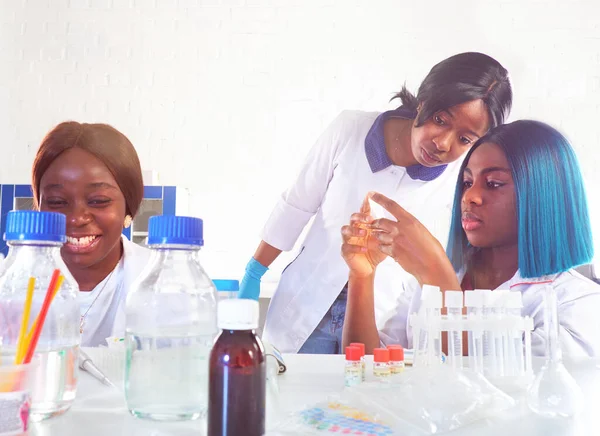 Development of vaccine protecting people from novel coronavirus causing covid-19 viral pneumonia pandemic outbreak worldwide. Three energetic African female women scientists or students working in lab