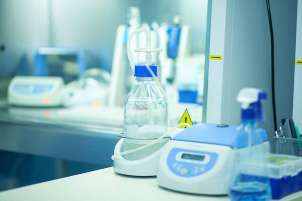 Scientific background with buffer solutions in glass bottles and liquid scientific or medical samples in various glass and plastic tubes. Shallow DOW, toned image.