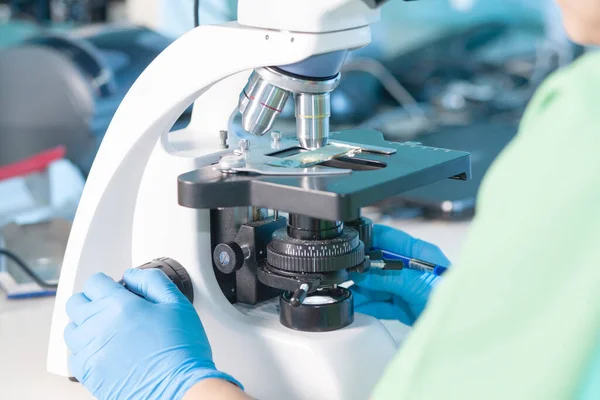 Üniformalı kadın profesyonel, elleri eldivenli. Araştırma laboratuvarında ya da laboratuarda ışık ya da floresan mikroskobuyla çalış. Sağlık görevlileri ya da üniversite öğrencileri için tarih ya da histopatoloji eğitimi.