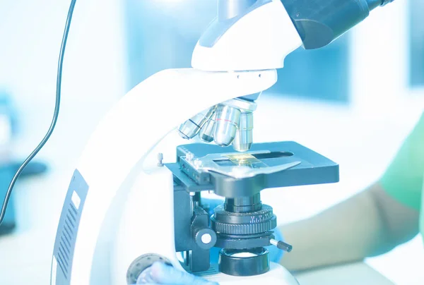 Üniformalı kadın profesyonel, elleri eldivenli. Araştırma laboratuvarında ya da laboratuarda ışık ya da floresan mikroskobuyla çalış. Sağlık görevlileri ya da üniversite öğrencileri için tarih ya da histopatoloji eğitimi.