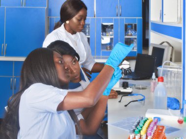 Genç Afrikalı kadın teknisyenler veya bilim adamları test laboratuarında tıbbi kan örnekleriyle çalışıyorlar. Viral pnömoni Covid-19 veya hafif solunum semptomları olan hastalardan alınan örneklerin taranması.