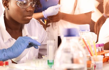 Afrikalı kadın tıp öğrencileri, araştırma laboratuvarında ya da tıbbi test laboratuvarında çeşitli testler yapan genç mezunlar. Kadın araştırmacı, DNA 'yı otomatik pipette ile güçlendiriyor.