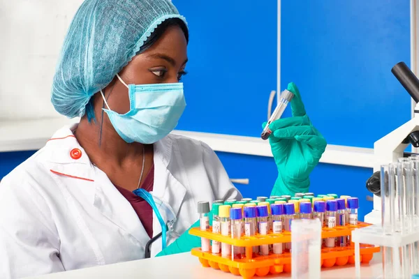 Arican tıbbi teknisyeni hasta kan örneğinin etiketini kontrol ediyor. COVID-19 salgınlarıyla savaşmak, hastanın kanında SARS-CoV-2 virüsü ve antikorları test etmek..