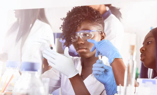 Female African medical students in research laboratory or medical test lab making various testing on patients samples.Female researcher makes pcr reaction amplify DNA with automatic pipette.