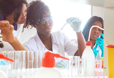 Test tesisi. Genç Afrikalı bilim adamları veya tıp öğrencileri, pozitif enerjik kadınlar, kan, nükleik asit ve Covid-19 hastalarından alınan örnekler üzerinde birlikte çalışırlar..
