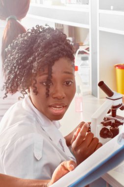 Genç Afrikalı kadın teknolojinin portresi ya da koruyucu gözlüklü bilim adamı test laboratuarında tıbbi kan örnekleriyle çalışıyor. Yeni koronavirüsün yol açtığı viral pnömoni Covid-19 hastaları test ediliyor..