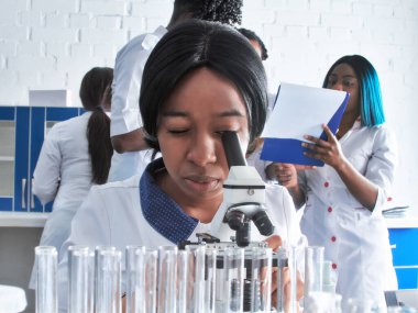 Genç zeki Afrikalı kadın bilim adamı, mezun ya da tıp öğrencisi test laboratuvarında ya da üniversite biyolojisi kursunda hasta biyopsisi örneklerini mikroskopla gözlemler. Pratik anatomi kursu.