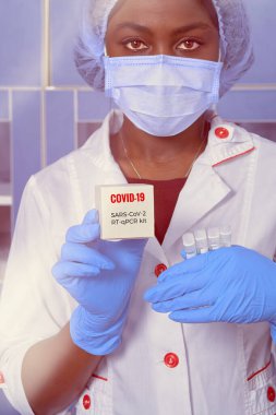 Afrikalı bir tıp öğrencisinin portresi, beyaz önlüklü kadın bilim adamı, plastik şapka, eldiven, maske pipette, PCR nükleik asit DNA Corona virüsü testi, hastalarda covid-2019 teşhisi.