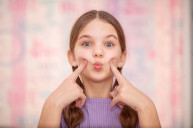 Genç kız sosyal ağda arkadaşları ve takipçileri için yaratıcı içerikler yaratıyor. Gülen ergen, gülen surat yapar, seyircilerle şakalaşır, şakalaşır. Gençlerin modaya uygun yaşam tarzı.