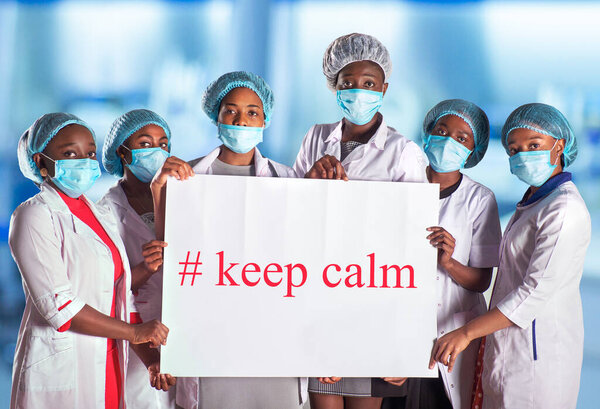 Group of African women nurses activists in face mask with hand sign placard with captions keep calm. Group of medics with message for public, information campain.