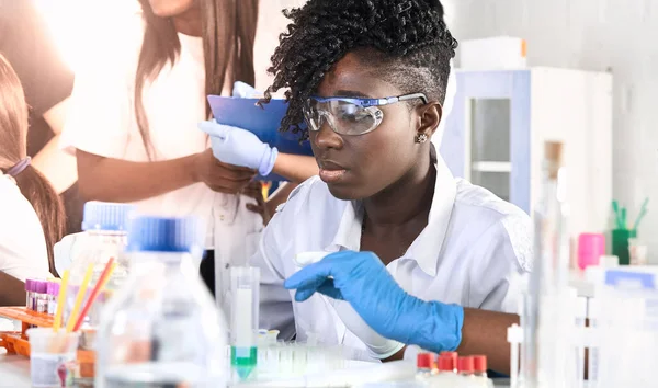 Afrikalı kadın tıp öğrencileri, araştırma laboratuvarında ya da tıbbi test laboratuvarında çeşitli testler yapan genç mezunlar. Kadın araştırmacı, DNA 'yı otomatik pipette ile güçlendiriyor.