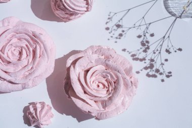 Güzel pembe dekoratif yenilebilir marshmallow gülleri, yaprakların arasından çekilen, bitkilerin ve çiçeklerin güzel gölgeleri, narin renkler, arka planın seçici bulanıklığı..