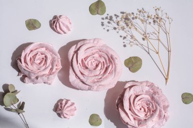 Lezzetli, havadar marşmelovlar gül şeklinde, pastel pembe kekler bir restoranda beyaz bir masada, yemek ve pasta için dekorasyon..
