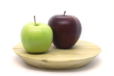 Beyaz arka planda izole edilmiş bir tabakta yeşil ve kırmızı elma.