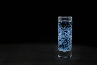 Siyah arka planda izole edilmiş baloncuklu bir bardak sıvı.