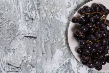 Ahşap bir arka planda, tabakta kırmızı üzüm.