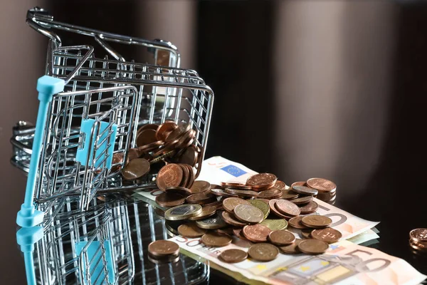 Paralı mavi alışveriş arabası. Yansıyan tablo. Karanlık arka plan. Mali işler. Finansal kriz. Bankacılık sistemi. Ekonomik bir sorun. Enflasyon. Para yazdırma.