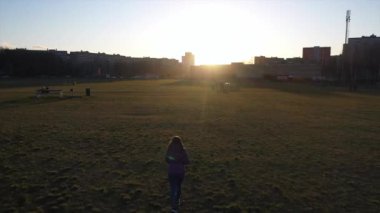 Kız gün batımında parkta yürüyor. Hava görüntüsü. Yavaş çekim