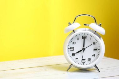 Mavi arka plandaki ahşap masada beyaz retro alarm saati