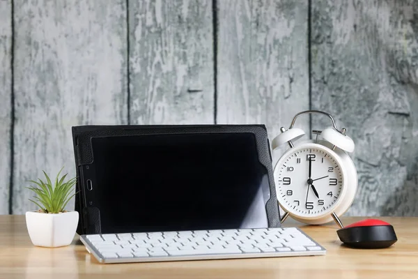 Tablet, computer mouse and keyboard on a table. Retro alarm clock. Wooden background. Work place. Finance. Freelance