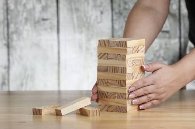 Masaya tahta tuğla koyan bir kız eli. Kule inşa oyunu.