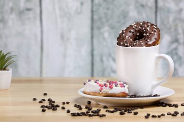 Beyaz kahve fincanı, üzerinde çikolata ve beyaz çikolatalı çörek olan ahşap bir masada. Sabah espresso. Sabah kapuçino bardağı.. 