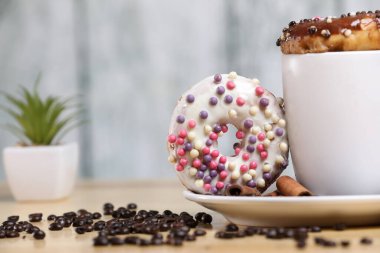 Beyaz kahve fincanı, üzerinde çikolata ve beyaz çikolatalı çörek olan ahşap bir masada. Sabah espresso. Sabah kapuçino bardağı.. 