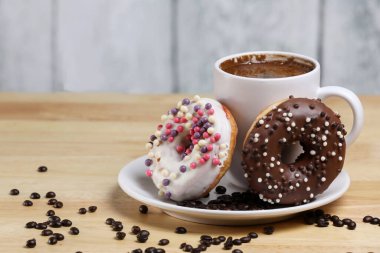 Beyaz kahve fincanı, üzerinde çikolata ve beyaz çikolatalı çörek olan ahşap bir masada. Sabah espresso. Sabah kapuçino bardağı.. 